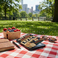 Book Club Alibi board game with berries, notebook, pen, and sunglasses on a picnic blanket.