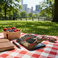 E-reader with "Read the Clues" case, berry basket, notebook, sunglasses on picnic blanket.