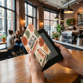 E-reader cover with "REST IS PRODUCTIVE" text, set in a cafe.