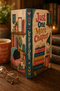 Book-shaped box with 'Just One More Chapter' design on a wooden surface with glasses and a mug.