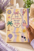 Hand holding personalized Mom keepsake journal next to lavender flowers and beverage glass