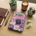 Journal, pen, candle, alarm clock beside a purple planner with quotes and a to-do list.