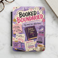 Planner with "Booked & Boundaried" and affirmation notes, a book, and teacup.