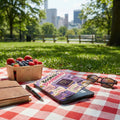 E-reader with "Booked & Boundaried" case, a berry basket, notebook, pen, and sunglasses.