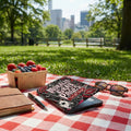 E-reader with "Moral Gray Pages" cover, fruit basket, journal, pen, and sunglasses on picnic blanket.